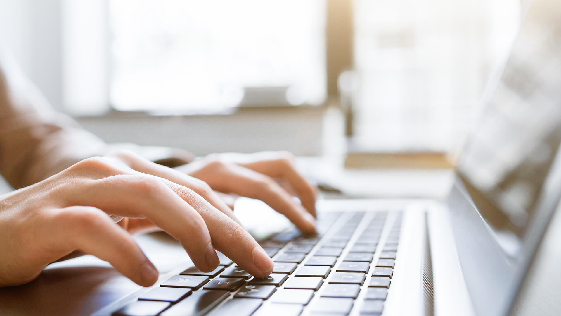 Close-up of someone typing on a laptop